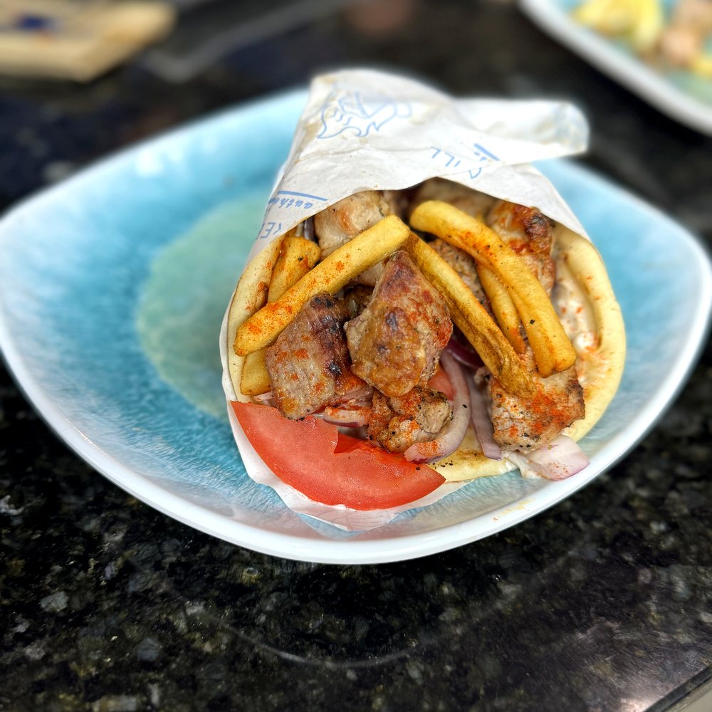 Flame-grilled gyro wrap with fries, tomato, and red onion
